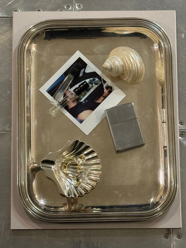 Silver tray styled with a shell ashtray, lighter, perfume, and a photo card.